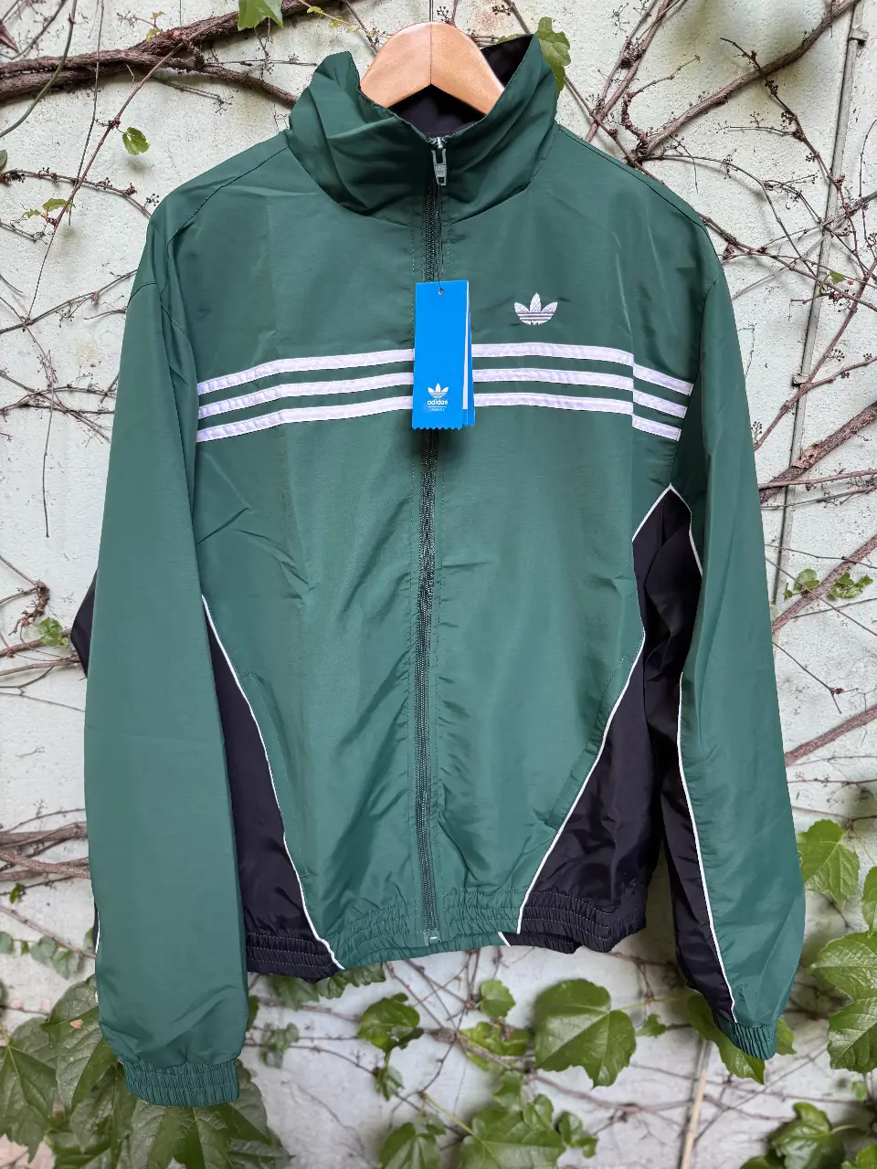 Campera deportiva Adidas verde con detalles en negro y blanco. Con cierre, logo de la marca y tres tiras blancas. Ideal para un look casual y deportivo. Replica triple A