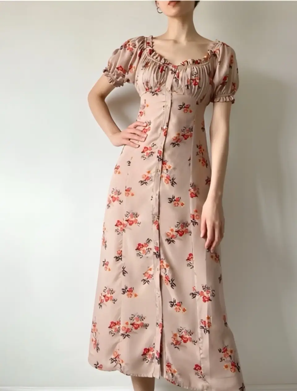 Vestido largo de estilo romántico con estampado floral. Presenta un diseño con botones frontales, mangas cortas abullonadas y un escote delicado. Ideal para un look femenino y fresco