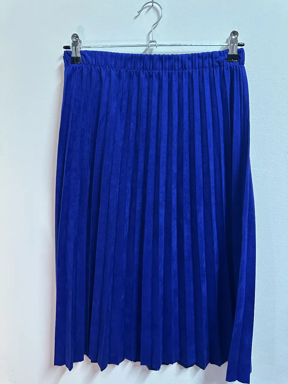 Pollera midi plisada de color azul. Confeccionada en tela de terciopelo, tiro alto y cintura elastizada. Ideal para un look elegante y sofisticado.
