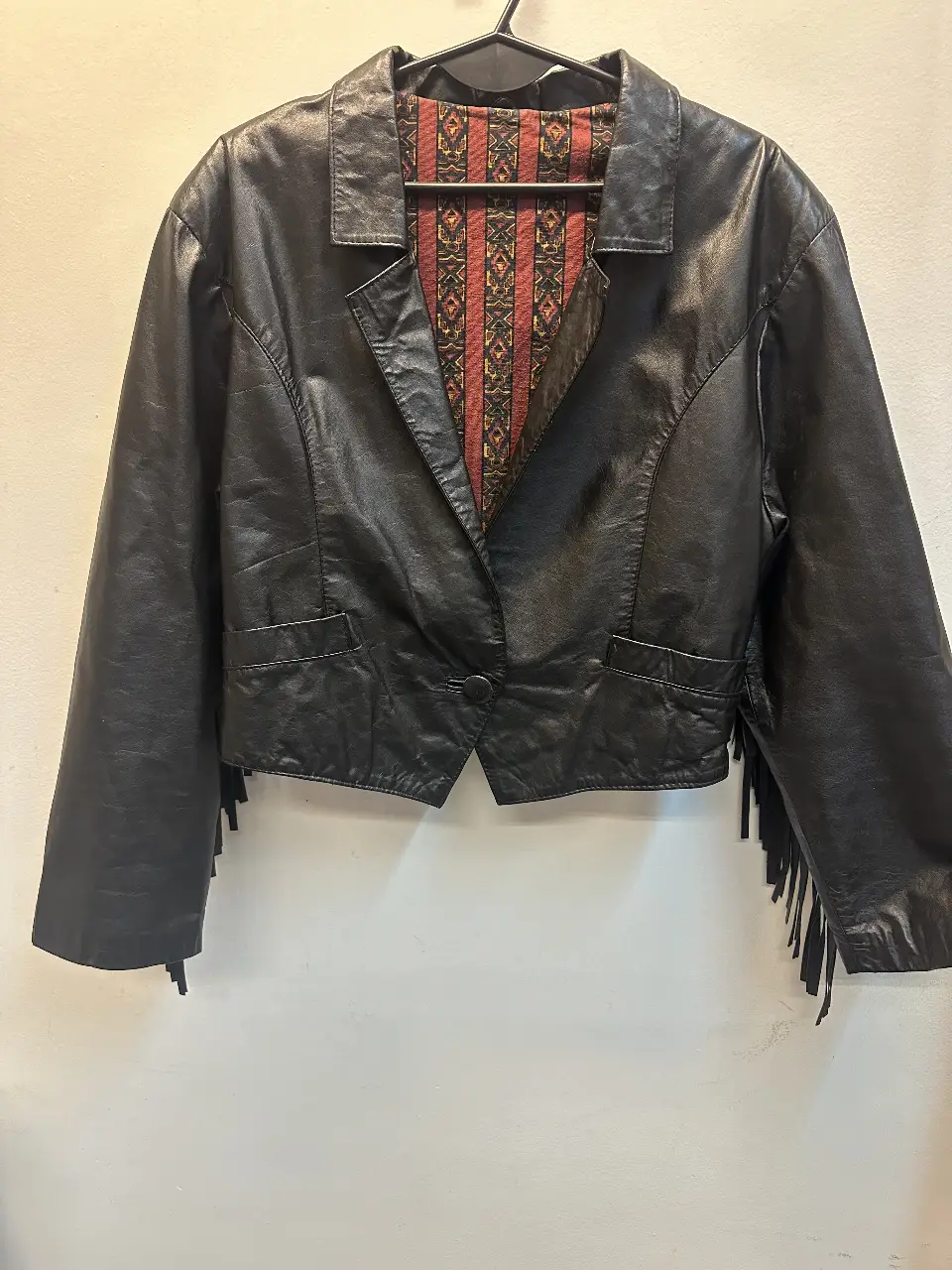 Campera de cuero negra con flecos en la espalda y detalles de diseño. Interior con forro estampado. Talle L.