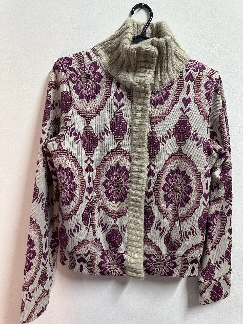 Cardigan de mujer con diseño floral en tonos violetas y beige. Cuello alto y cierre frontal con botones. Interior forrado en tela suave.