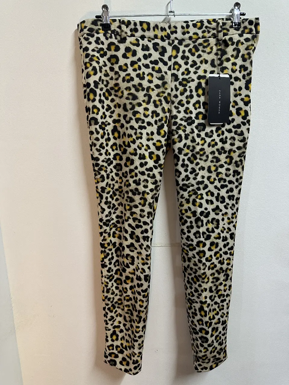Pantalón de mujer estampado con diseño de leopardo. Tiro alto, con cierre y etiqueta de la marca Zara Woman. Ideal para un look moderno y audaz.
