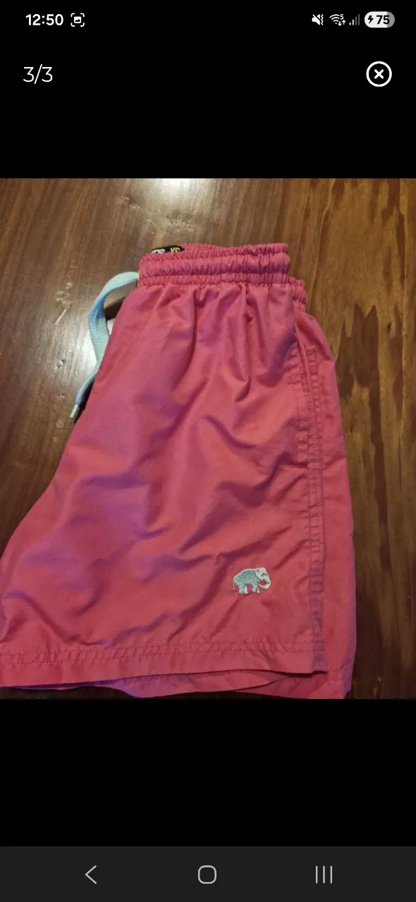 Shorts de baño color rosa con cordón de ajuste celeste y logo de elefante bordado en la parte inferior izquierda. Posee bolsillos laterales y un bolsillo trasero con botón.