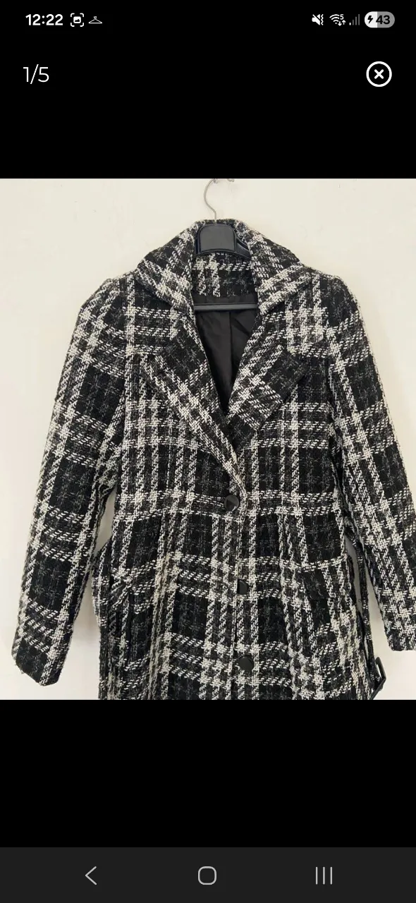 Campera de paño a cuadros escoceses en blanco y negro. Posee cuello solapa, dos botones al frente y cinturón de tela para ajustar.