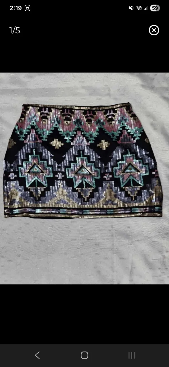 Pollera corta con lentejuelas y diseño geométrico bordado. La base es negra y las lentejuelas forman un patrón de rombos y líneas en tonos dorados, plateados, celestes y rosas.
medidas: cintura 38cm, largo35