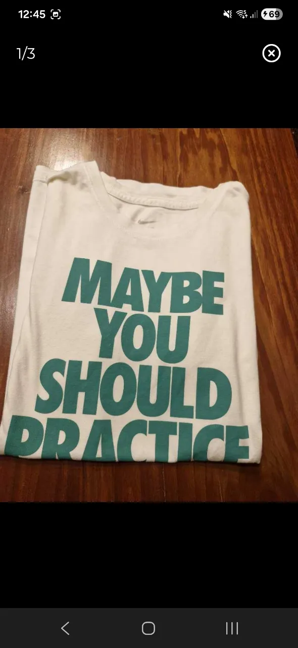 Remera blanca de manga corta con estampa "MAYBE YOU SHOULD PRACTICE" en color verde. Tiene un pequeño logo de Nike en la parte inferior.