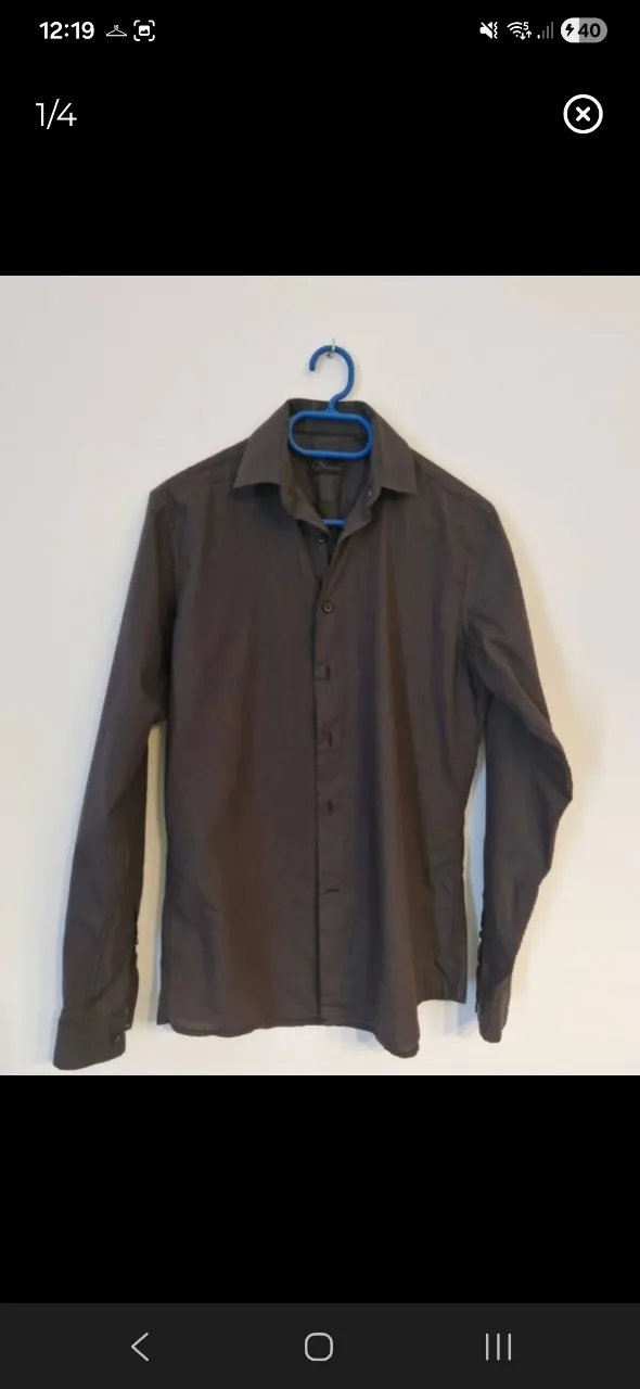 Camisa de manga larga de color gris oscuro. Posee cuello clásico y botones al frente.