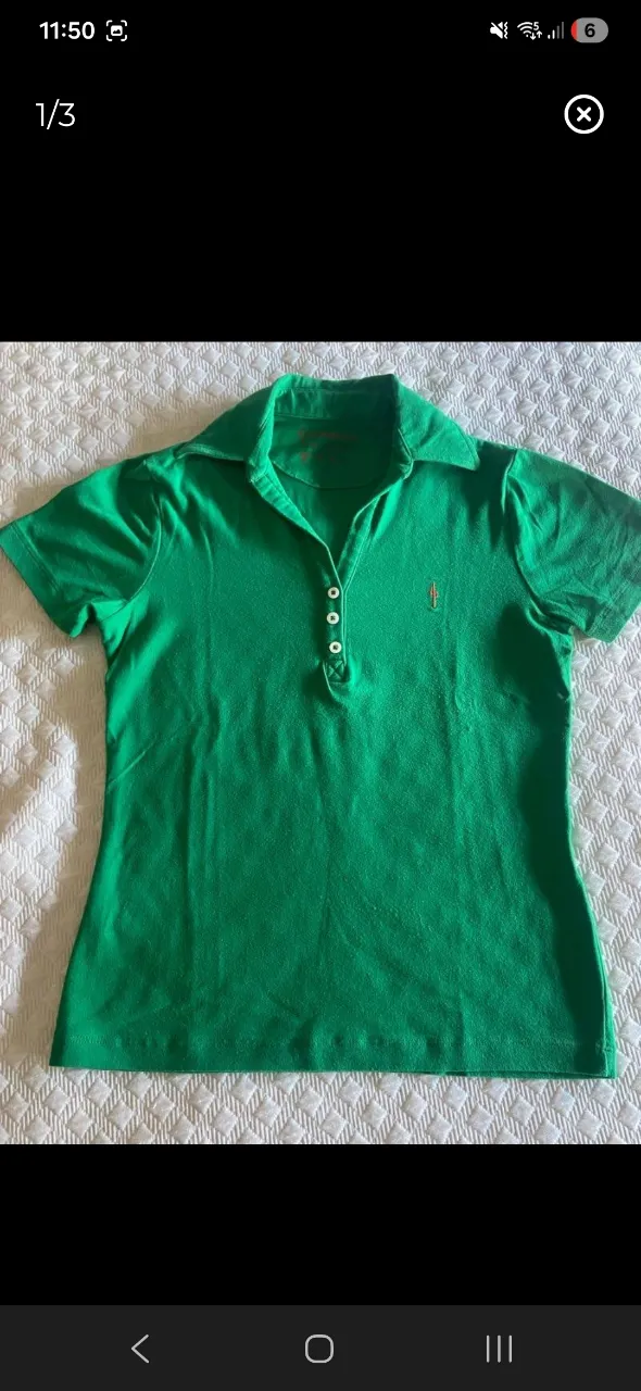 Remera polo verde con cuello y botones blancos. Tiene un pequeño bordado naranja en el pecho.