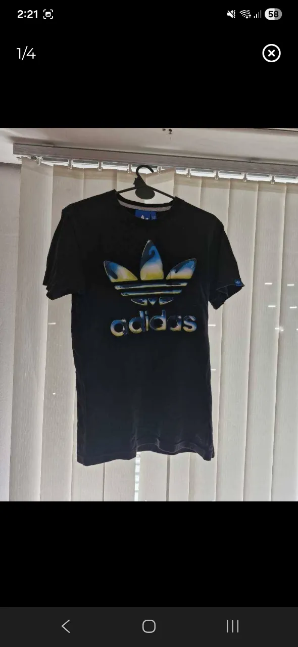 Remera negra de manga corta con estampa del logo de Adidas en el frente. El logo es tridimensional y tiene colores degradados entre azul, amarillo y blanco.