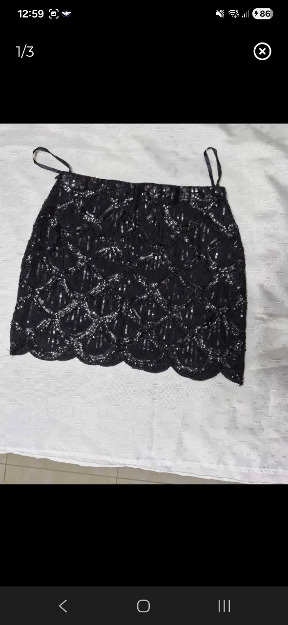 Pollera negra corta con lentejuelas plateadas en forma de escamas. Tiene tiras finas para colgar.
cintura 34. largo 36