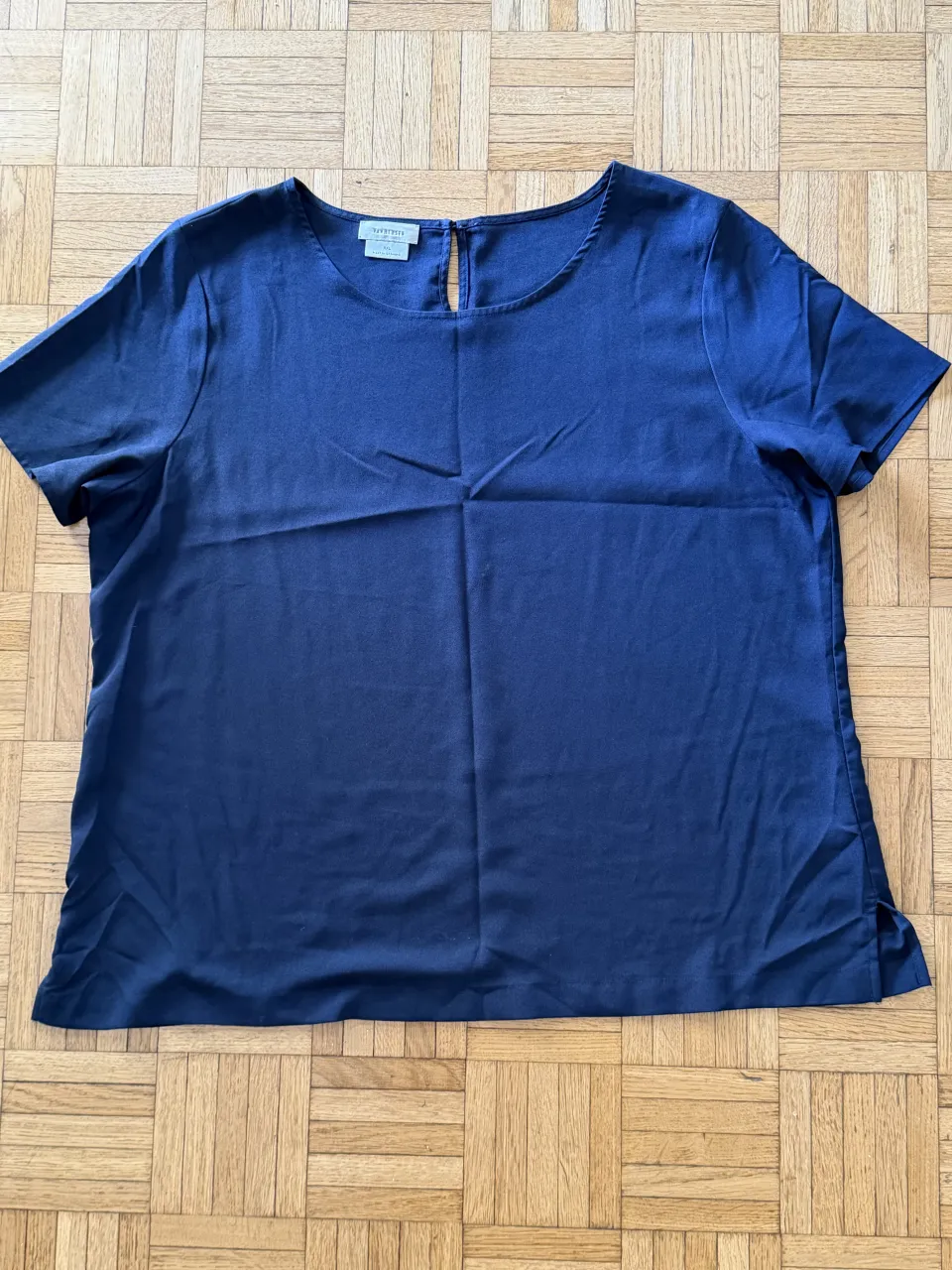 Remera azul de manga corta con cuello redondo y una pequeña abertura en la parte trasera superior.