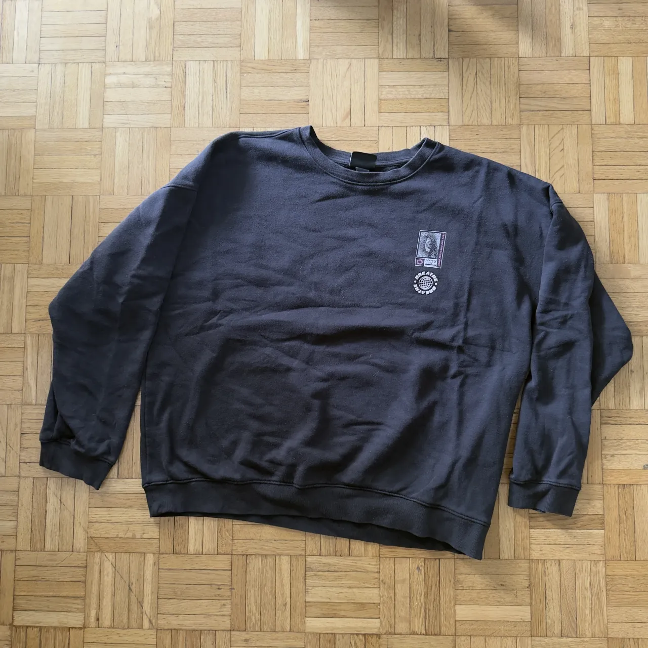 Buzo de algodón gris oscuro con estampa "BREATHE" en color rosa flúor y "FEEL THE PRESSURE DROP" en la parte frontal. Cuello redondo y mangas largas.