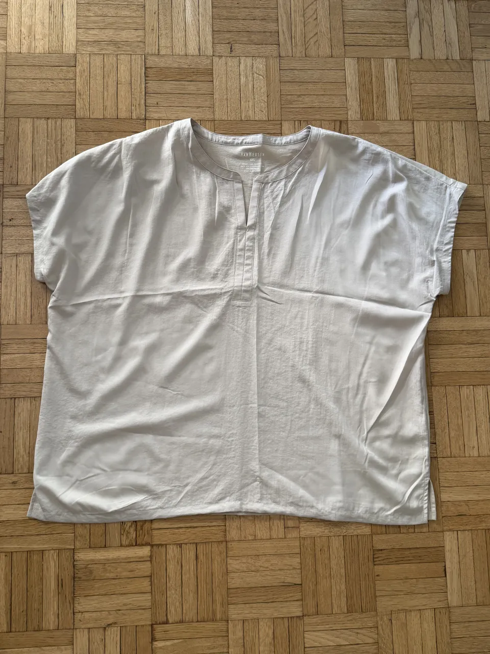 Remera de color blanco roto, con cuello mao y manga corta. Posee una abertura en el cuello con dos botones.