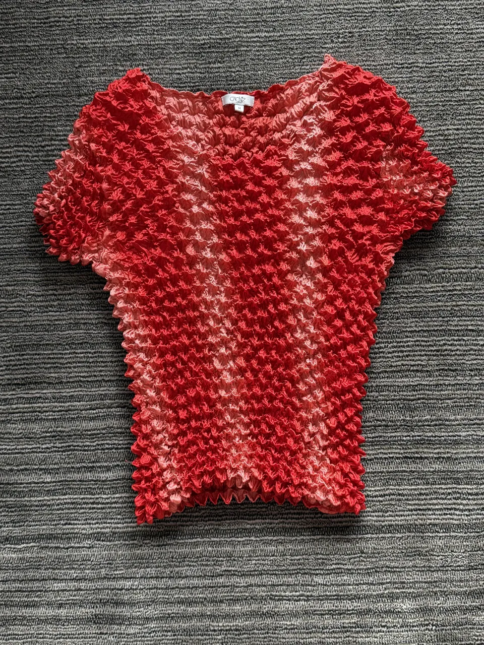 Remera de manga corta con textura fruncida y degradado de color rojo y rosa.