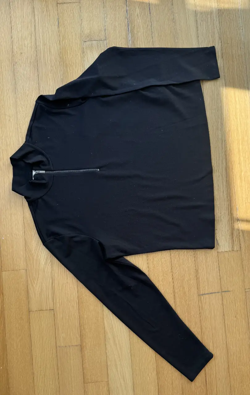 Buzo negro de H&M con cierre frontal y cuello alto. Ideal para un look casual y liviano.