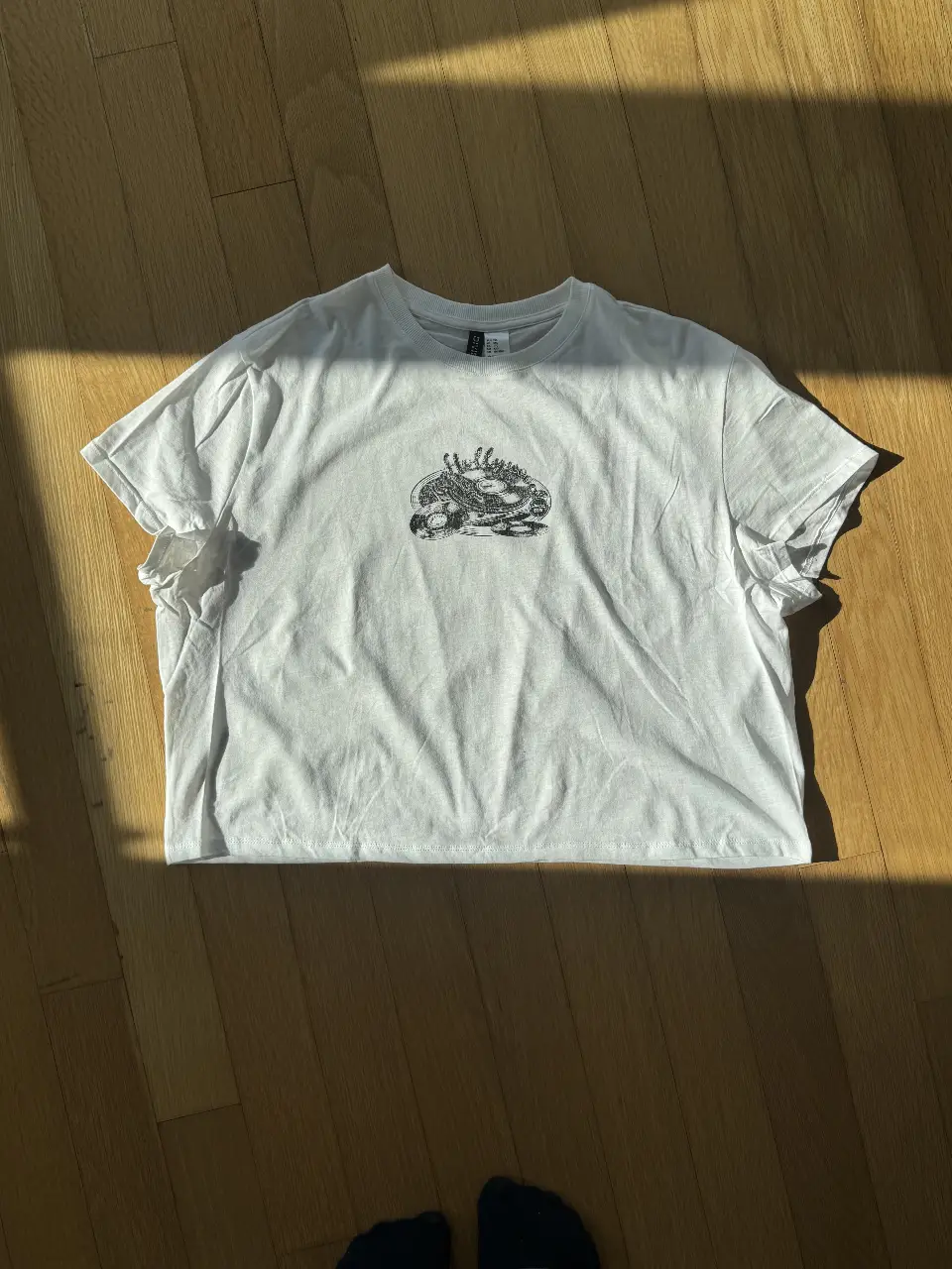 Remera H&M blanca de manga corta con estampado en el frente. Estilo crop top suelto, talle XXL. 