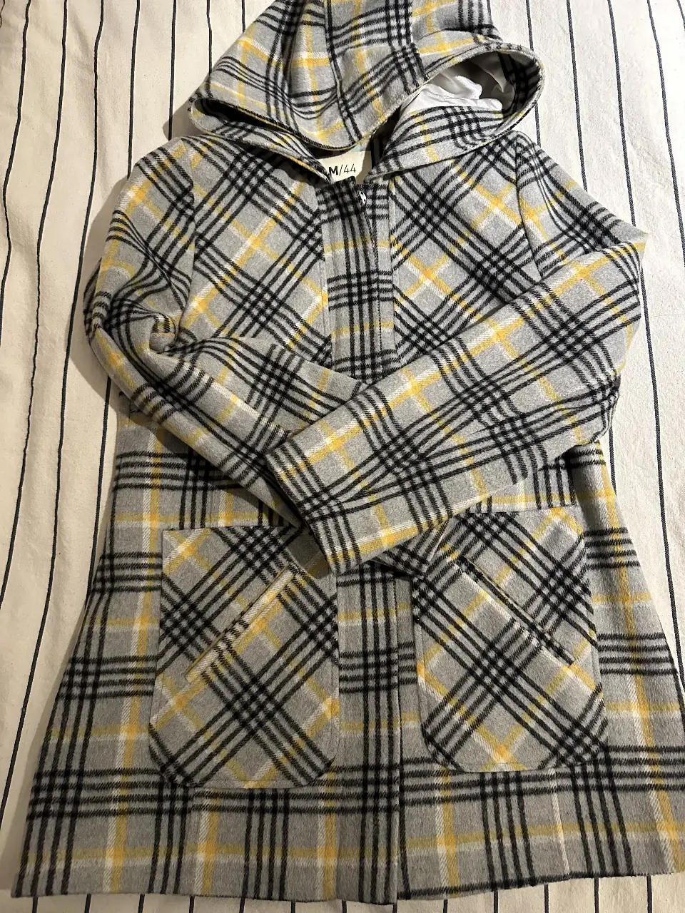 Tapado largo con capucha, estampado a cuadros en tonos grises y amarillos. Posee bolsillos delanteros y cierre frontal. Ideal para un look casual y abrigado. talle m ajustado. poquisimo uso. Ancho hombros: 36 cm. Largo: 70 cm