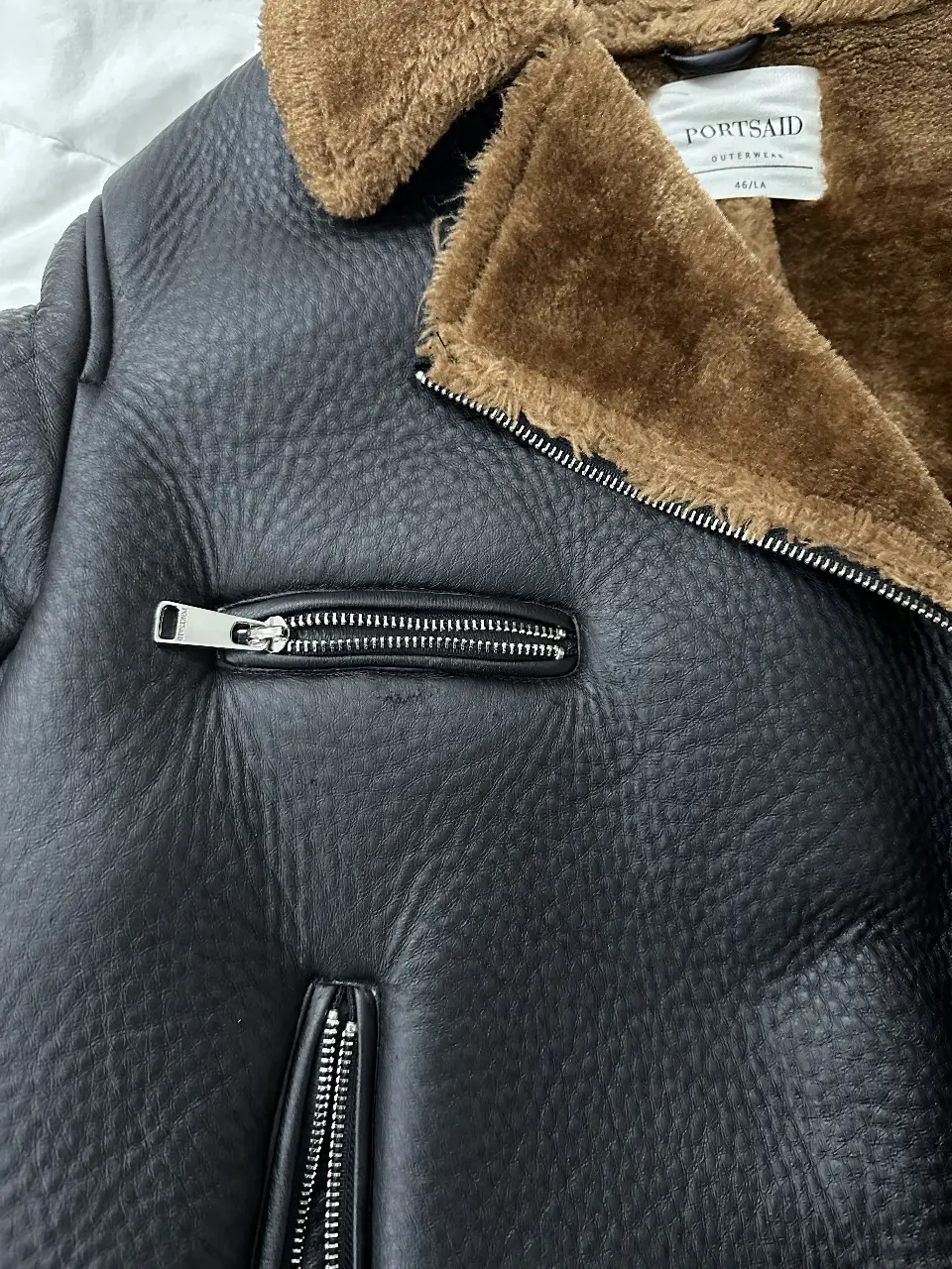 Campera de cuero sintético estilo gamulan para mujer, con cuello con solapas de piel sintética marrón, cierre y bolsillos con cremallera. Ideal para un look urbano y moderno. Va para un M