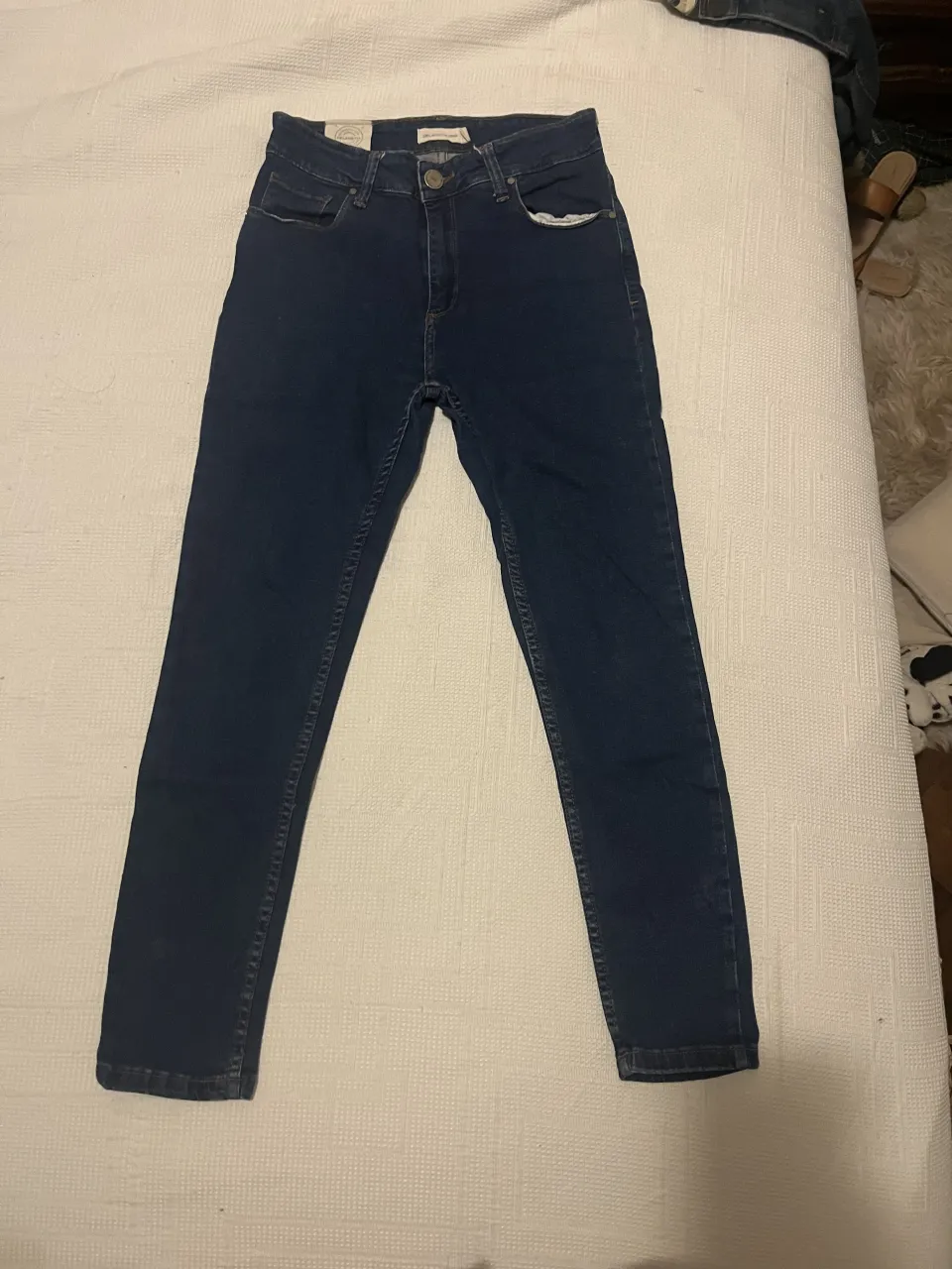 Jeans estilo chupin, color azul oscuro marca DELAOSTIA. Cuentan con bolsillos delanteros y traseros.