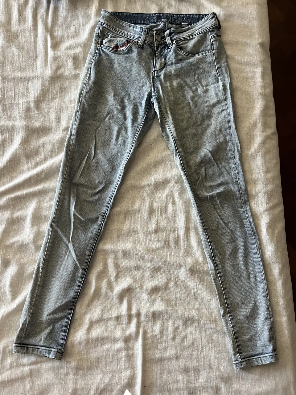 Jeans tiro medio/bajo de algodón , color celeste desgastado. Marca kosiuko. Presentan un botón metálico en la cintura.