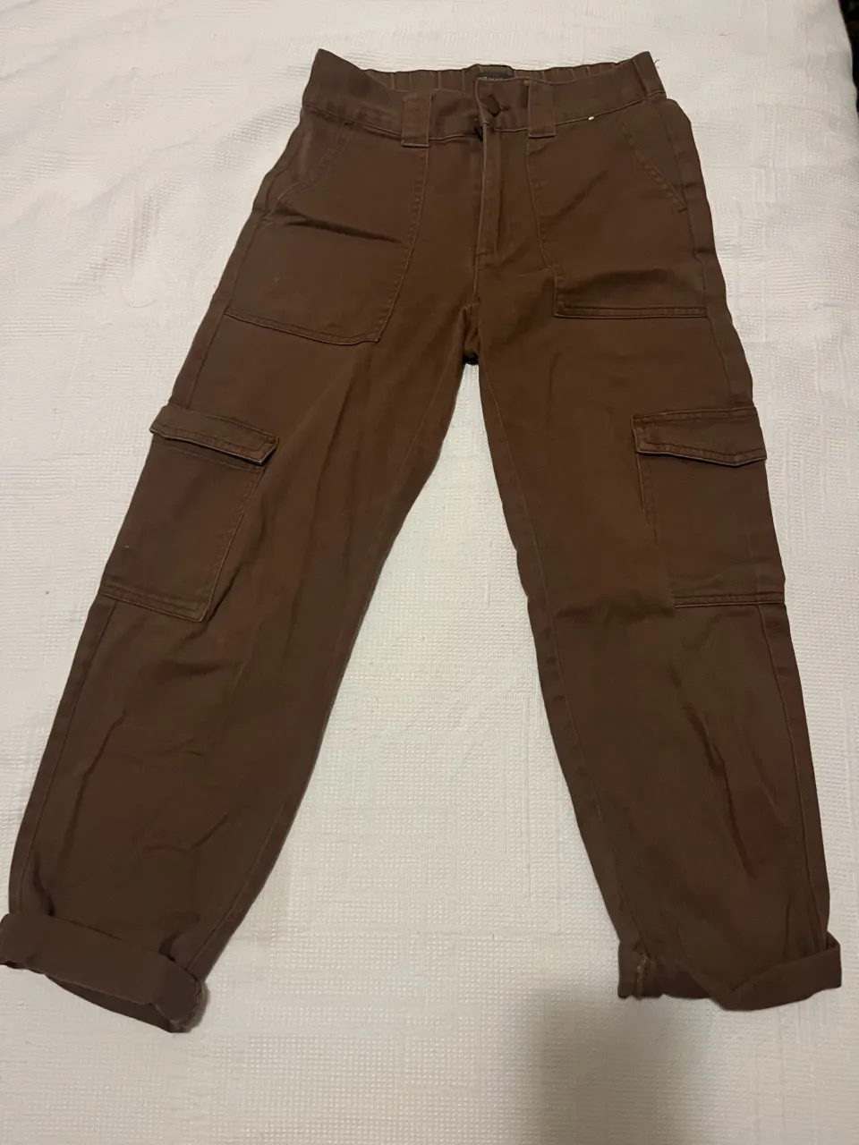 Pantalón cargo de color marrón. Posee bolsillos frontales y laterales con tapa.