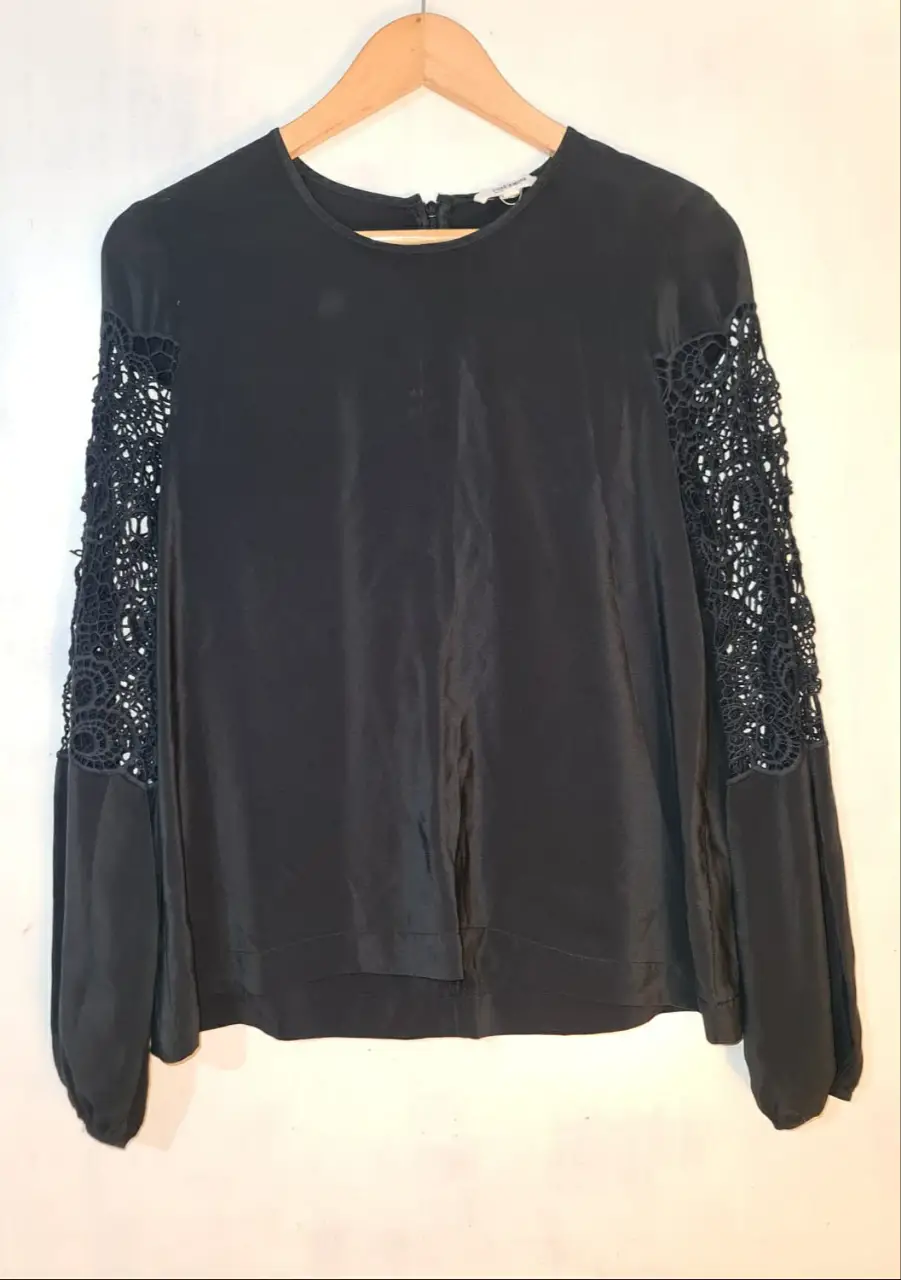 Blusa negra de seda con mangas largas y detalles de encaje. Ideal para un look elegante y sofisticado.