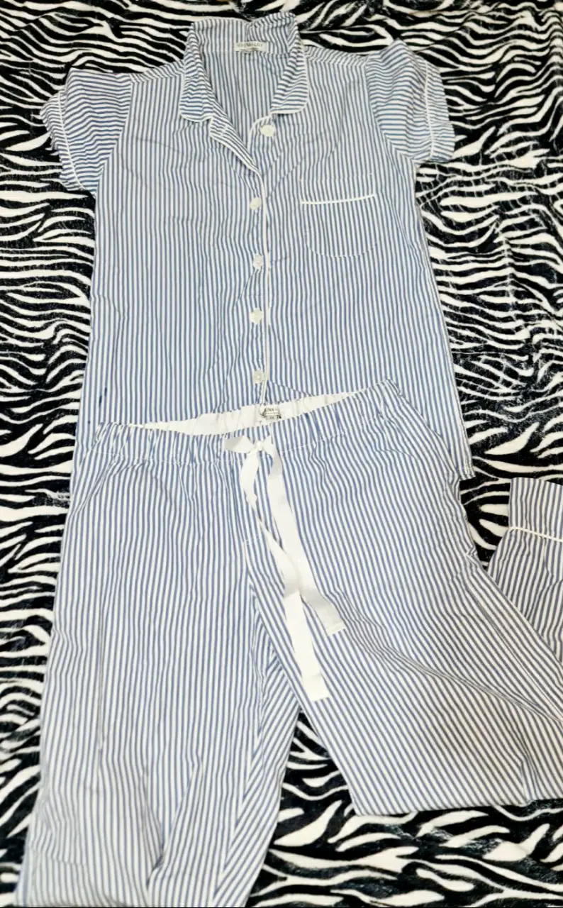 Pijama de dos piezas a rayas azul y blanco de la marca Serena & Lily. Incluye camisa de manga corta con botones y pantalón largo con cordón en la cintura. Ideal para un descanso cómodo y con estilo.