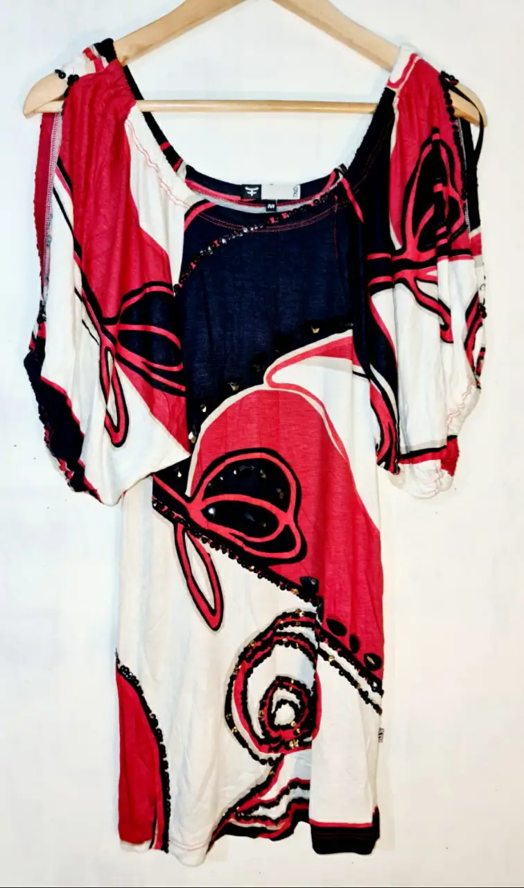 Blusa de mujer con estampado abstracto en rojo, blanco y negro. Diseño con hombros descubiertos y detalles de lentejuelas. Ideal para un look casual y moderno.