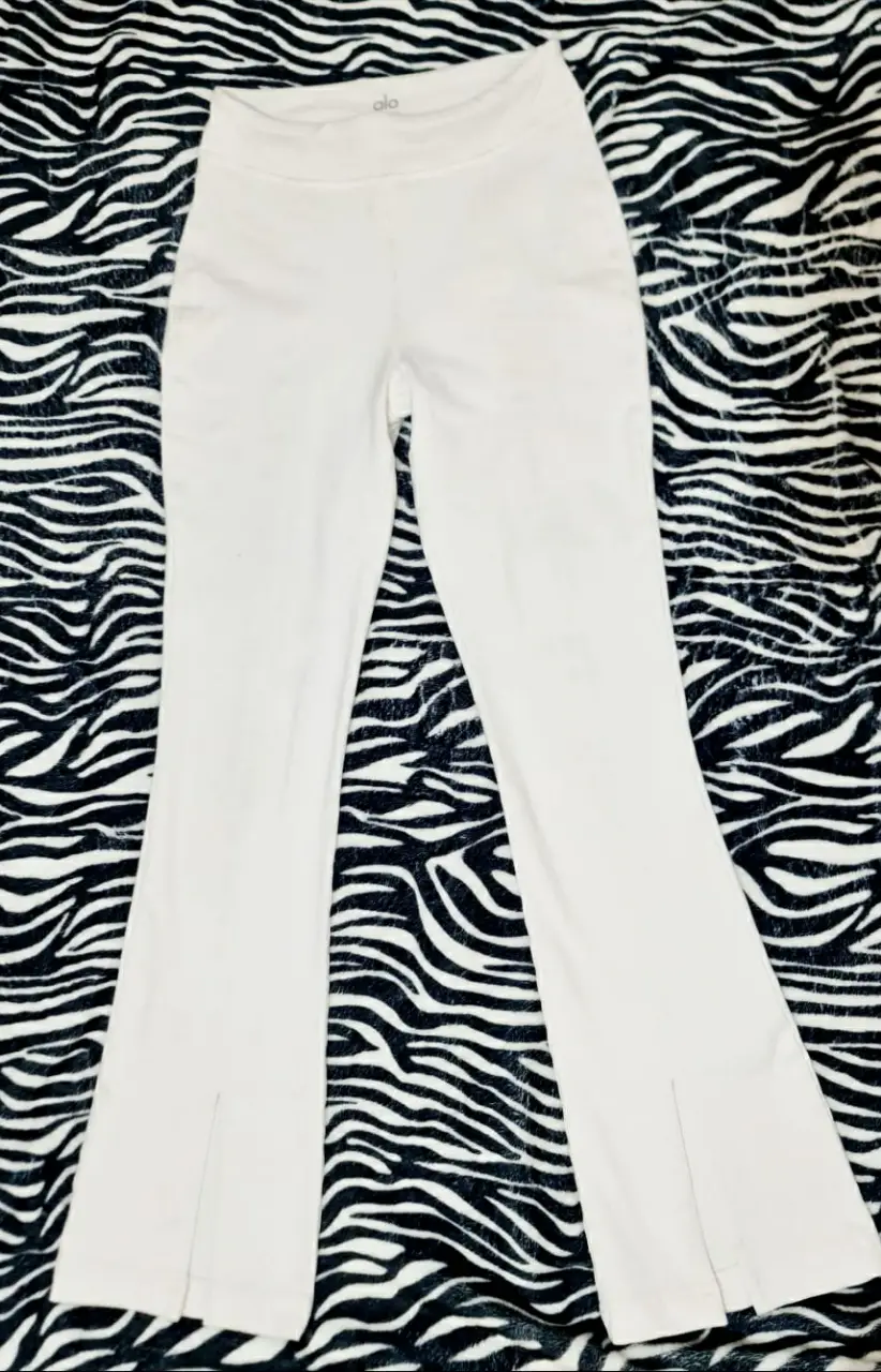 Calza color blanco, de la marca ALO YOGA, talle XS (sede bastante). Diseño con abertura en el bajo. Ideal para un look casual y cómodo. ORIGINAL