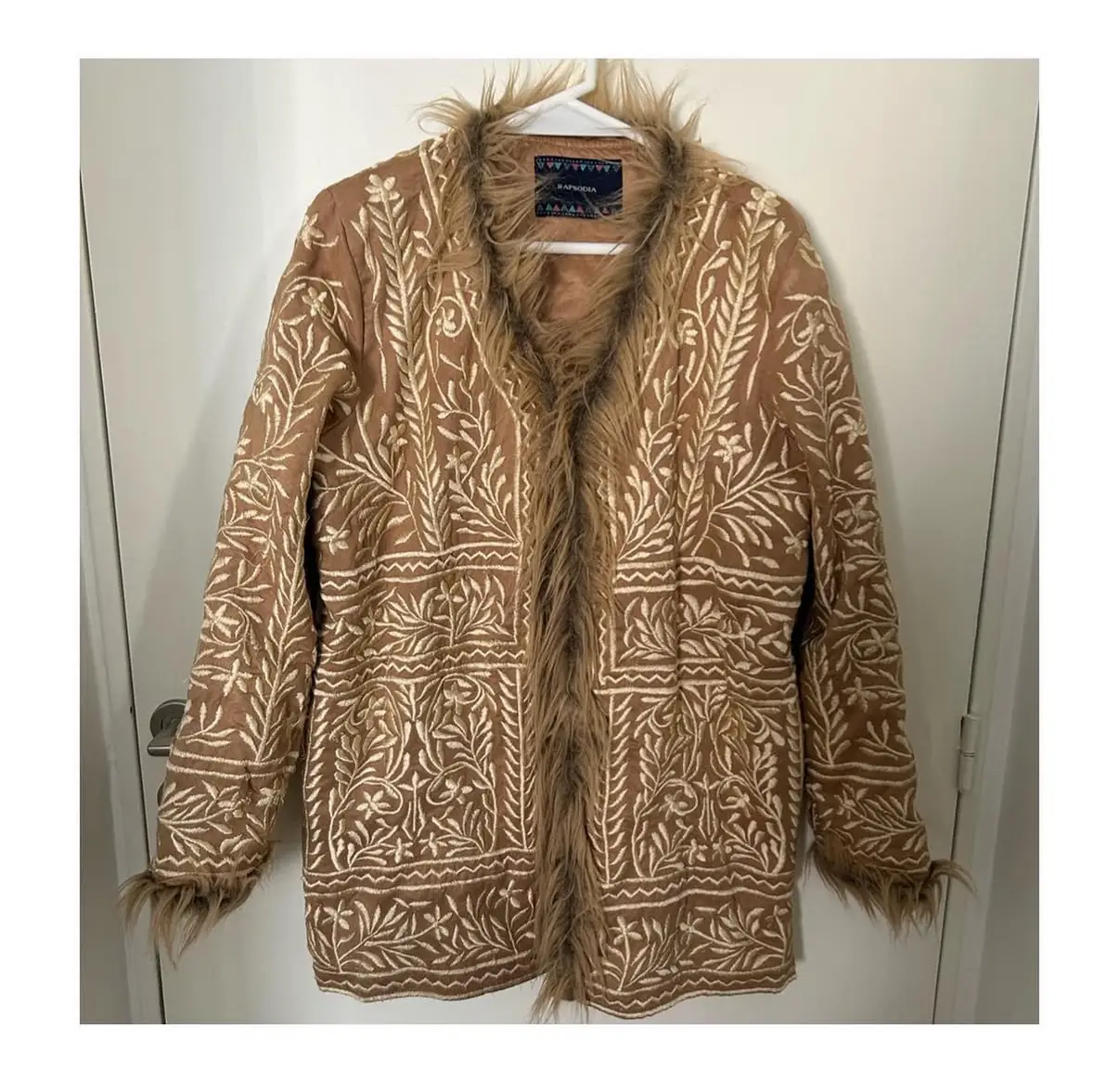 Campera estilo bomber con bordados florales en color marrón y detalles de piel sintética en el cuello y puños. Ideal para un look boho chic.