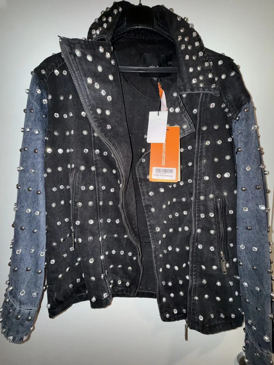 Campera de jean negra con detalles de tachas plateadas y mangas en denim azul. Estilo rocker y llamativo, ideal para darle un toque audaz a cualquier look.