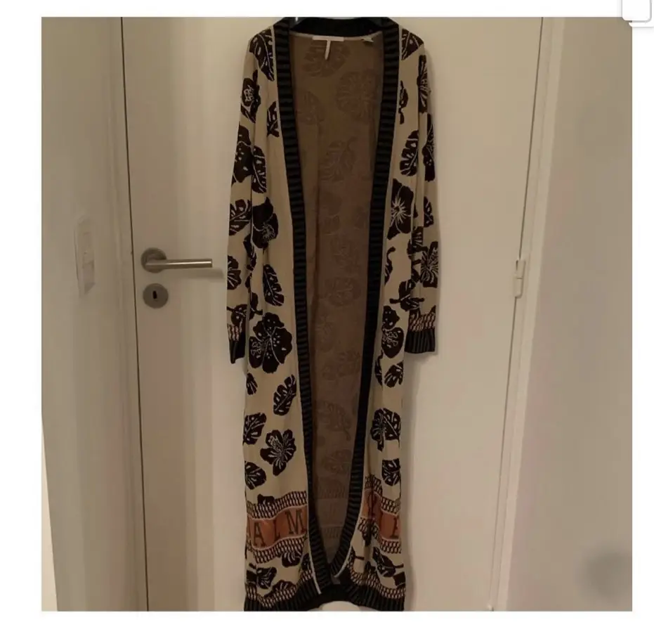 Cardigan largo con estampado floral en tonos crudo y negro. Ideal para un look bohemio y casual. Perfecto para usar sobre un vestido o con jeans.