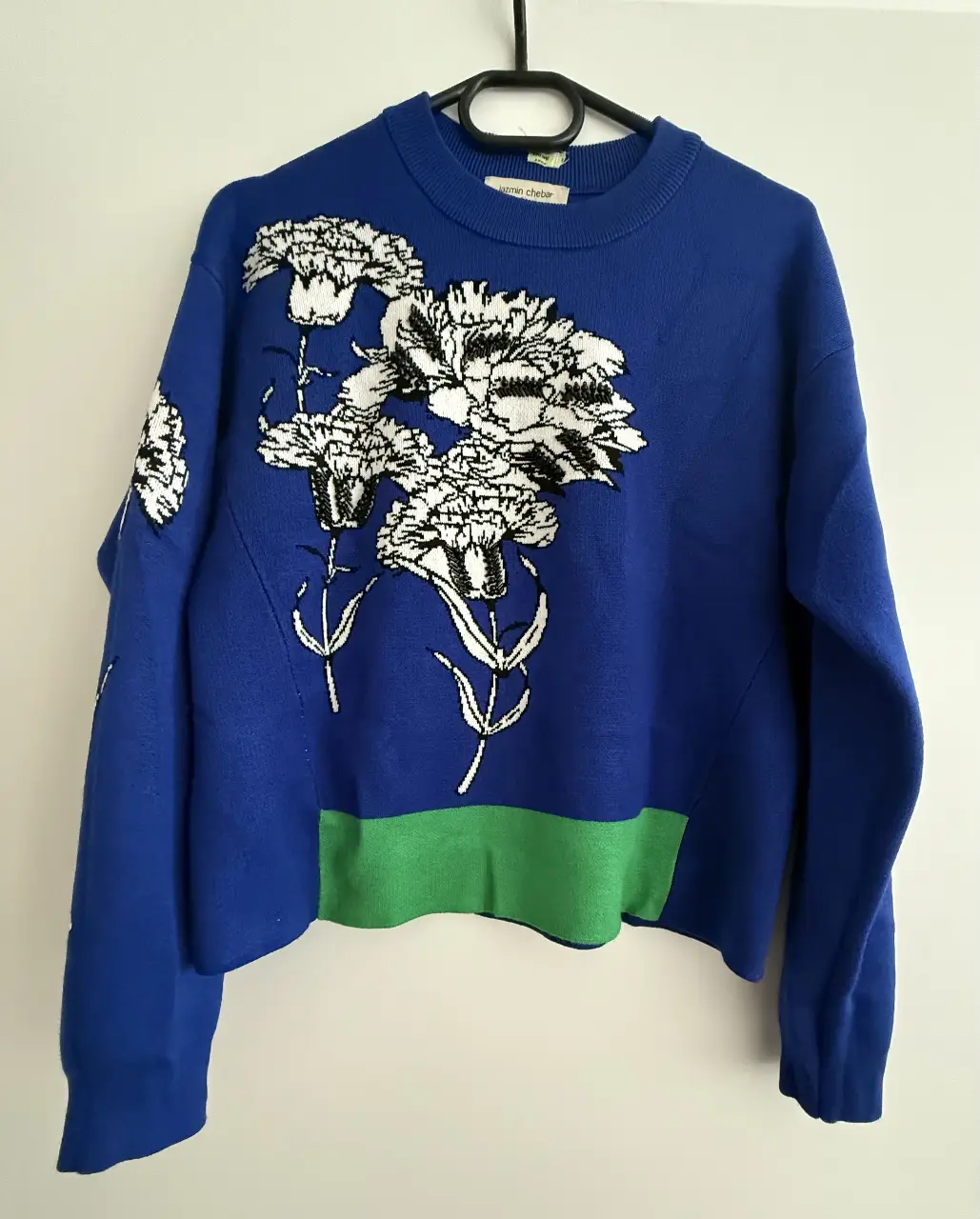 Sweater de mujer azul con diseño floral en blanco y negro. Detalles en verde en la parte inferior. Ideal para un look casual y moderno.