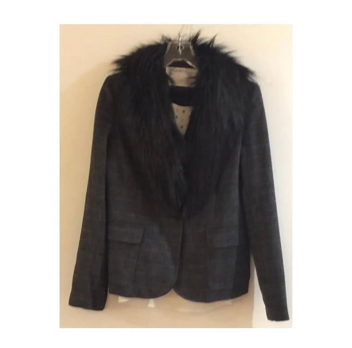 Elegante blazer de mujer de con cuello de piel sintética negra. Diseño a cuadros en tonos grises, con dos bolsillos frontales y cierre de un botón. Ideal para un look sofisticado y abrigado en invierno.