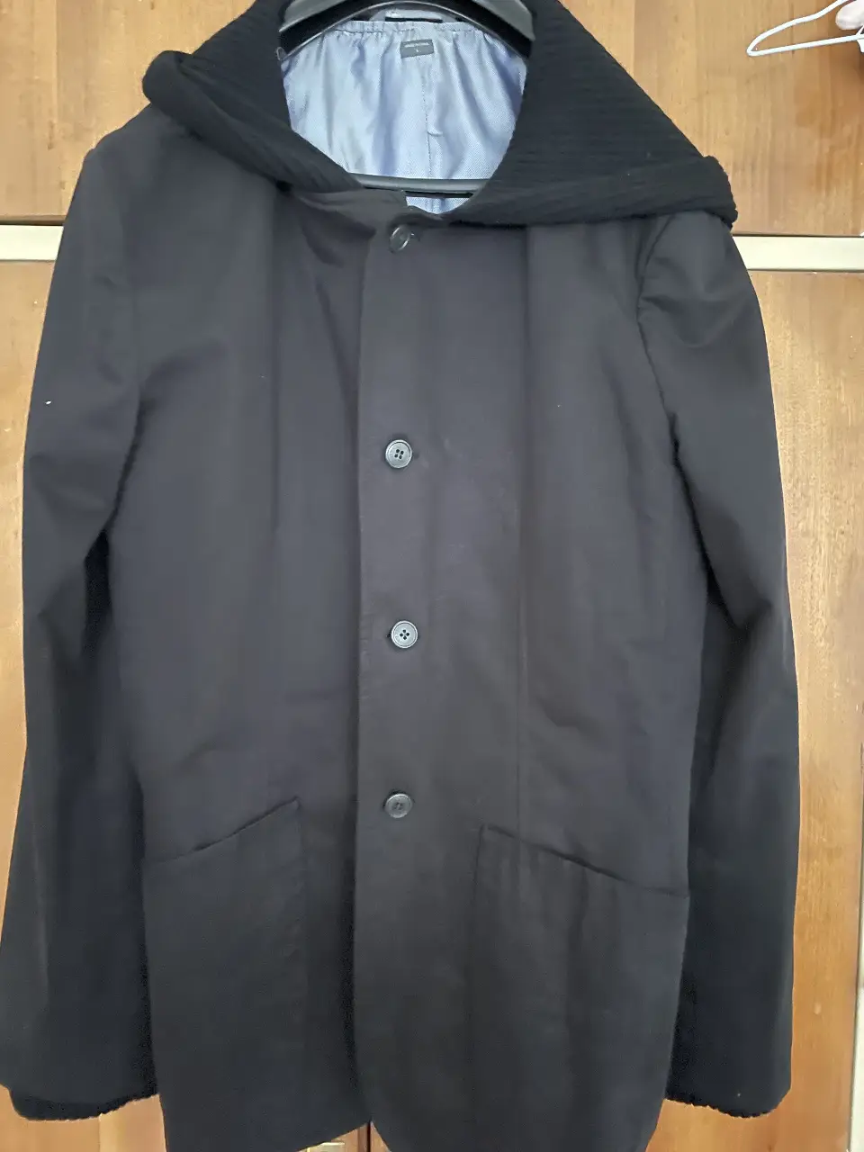 Abrigo  negro con capucha de tejido grueso, ideal para el invierno. Posee tres botones al frente y dos bolsillos laterales. Marca Armani Exchange.