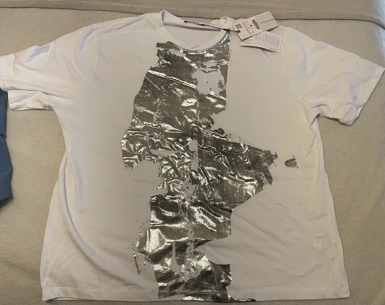 Remera blanca  con estampado foil plateado. Diseño moderno y casual, ideal para un look urbano.