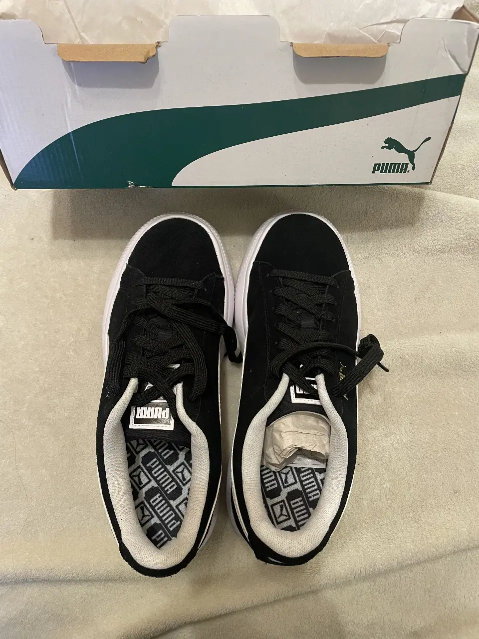 Zapatillas Puma negras con suela blanca, ideales para un look casual y urbano. Diseño clásico y cómodo, perfectas para el día a día.