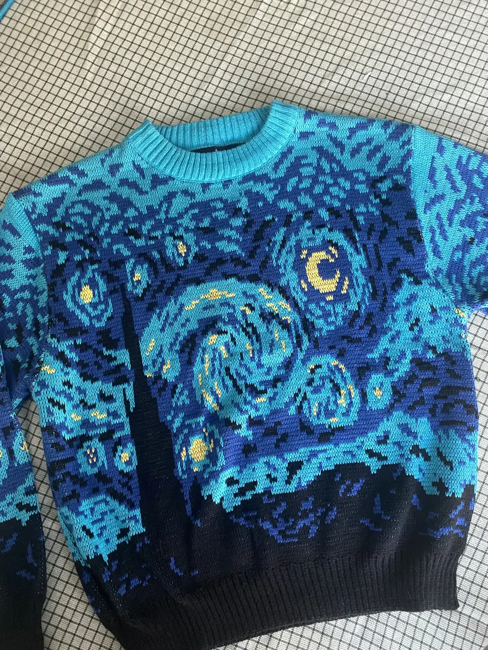 Sweater de diseño "La Noche Estrellada" de Van Gogh. Confeccionado en tejido de punto, este sweater presenta un cuello redondo y un ajuste regular. Ideal para un look artístico y abrigado.