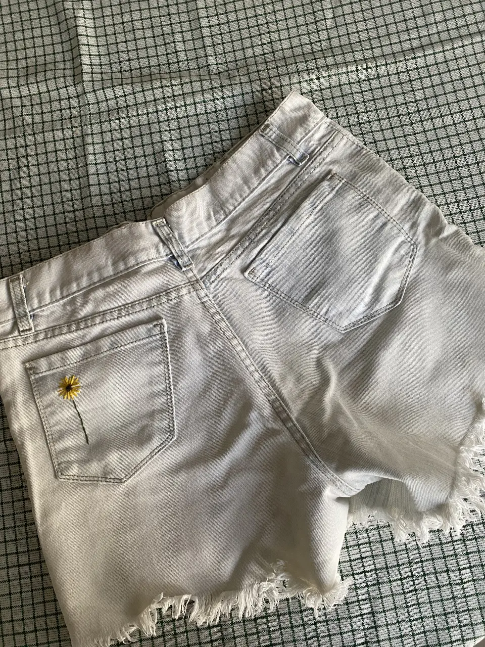 Short de jean blanco con toques de celeste con detalle de flor bordada en el bolsillo trasero, talle 38. Ideal para un look casual y fresco.