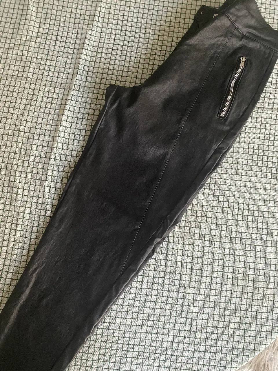 Pantalón de cuerina elastizada negro, con cierre y botón. Talle 38. Ideal para un look elegante y versátil.
