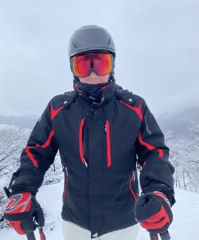 Campera de esquí Descente para hombre, color negro con detalles en rojo. Cuenta con cierre frontal, múltiples bolsillos y capucha. Ideal para la nieve y deportes de invierno.