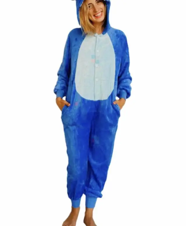 Pijama enteriza de diseño Stitch importado, con cierre de botones, capucha y bolsillos. Confeccionada en microfibra 100% poliéster, ideal para niños y adultos. Lavable en lavarropas.