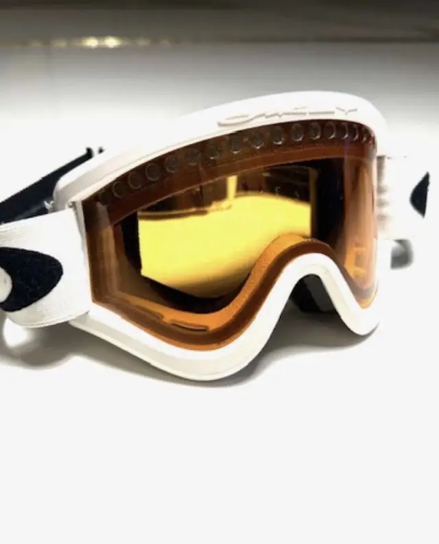 Antiparras Oakley blancas con lente amarillo, ideales para esquiar. Diseño deportivo y protección para la nieve.