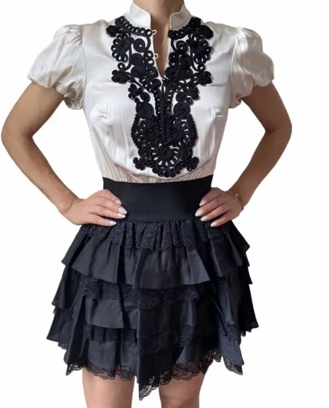Vestido mini de fiesta, con corpiño blanco con detalles bordados en negro y falda negra con volados. Marca Bebe, talle XXS.