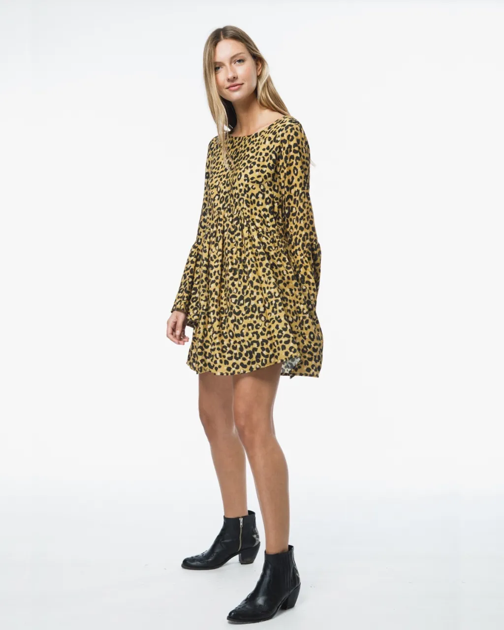 Vestido corto con estampa animal print de leopardo en tonos amarillos y negros. Posee mangas largas acampanadas y escote en V con detalle de tiras y pompones en la espalda. Ideal para un look canchero y moderno.