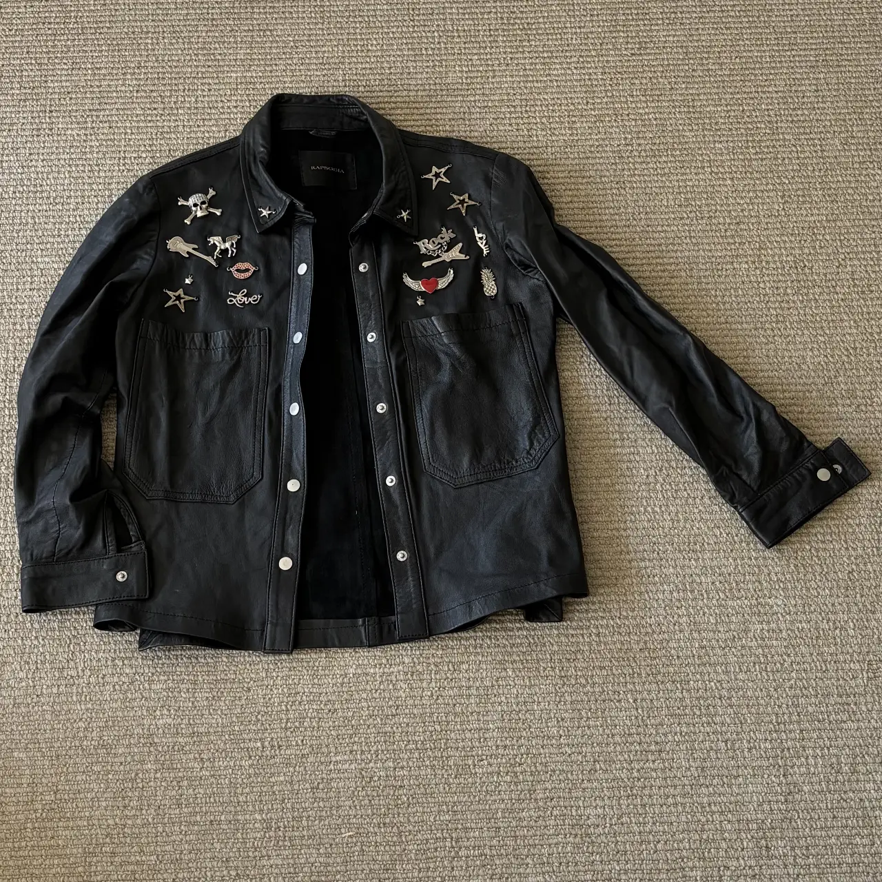 Campera de cuero negra con apliques de parches y bordados. Estilo rocker, ideal para un look casual y con onda.