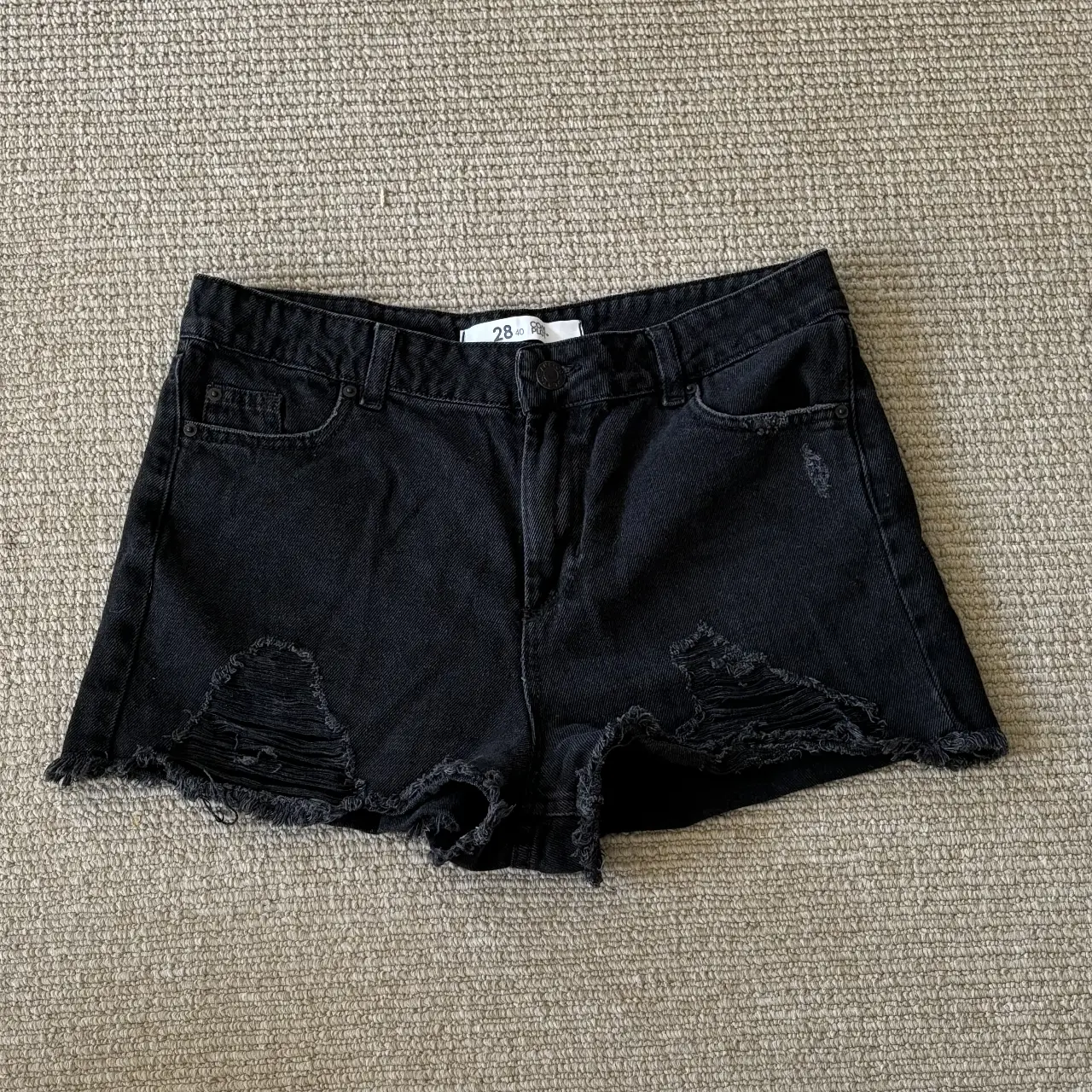 Short de jean negro con detalles rotos y desflecado. Talle 28, ideal para un look casual y moderno.