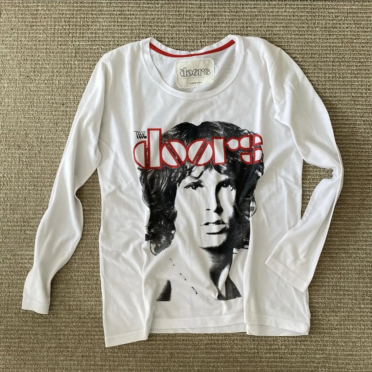 Remera manga larga blanca con estampado de la banda The Doors. Cuello redondo con detalle rojo. Estilo retro/vintage.
