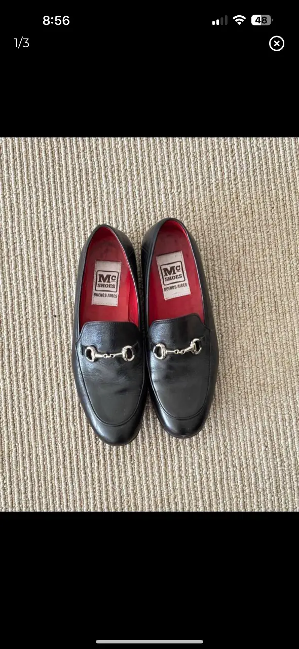 Mocasines de cuero negro con detalle de herraje plateado. Interior rojo con etiqueta de la marca MC Shoes Buenos Aires. Suela roja.