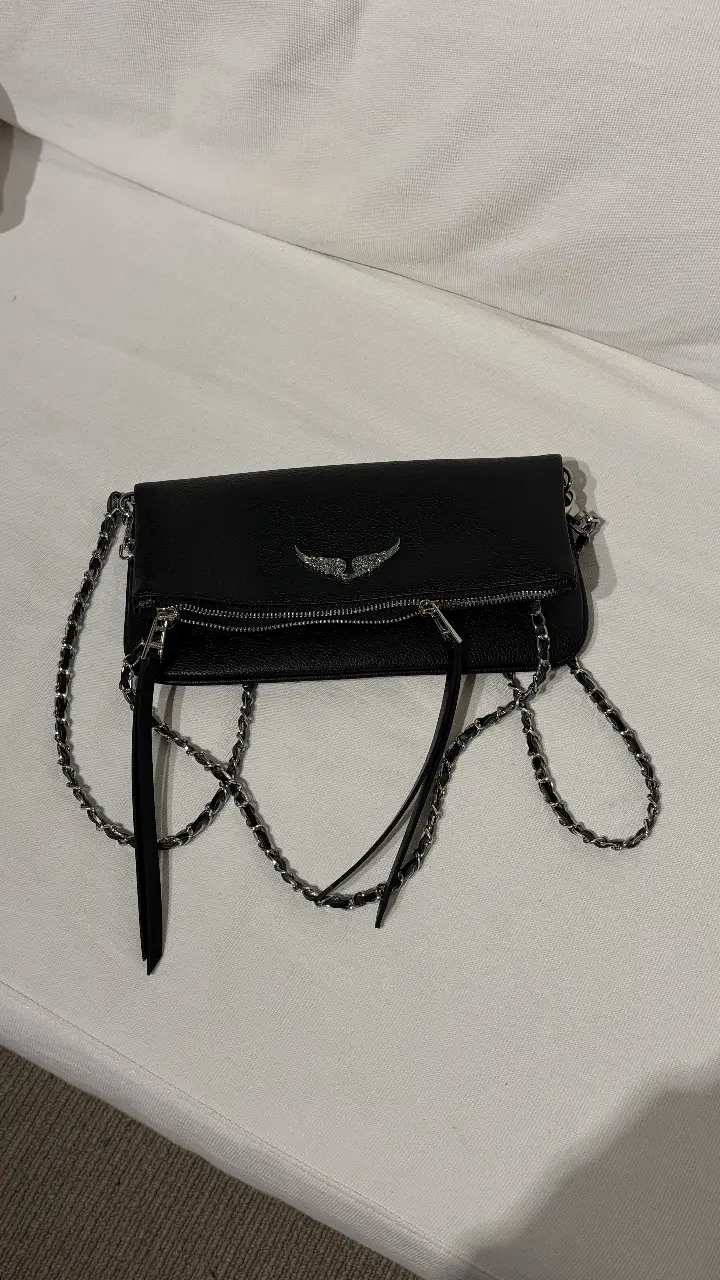 Cartera bandolera negra de cuero con detalles plateados y cadena. Ideal para un look moderno y elegante.